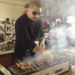 Alchemy chef Ricardo Heredia, sporting sunglasses, turns Japanese skewers over a smoky grill at his Street Food Market stand in the San Diego Public Market on March 24, 2013. (Photo by Cyndia Zwahlen for the Small Biz Mix.)