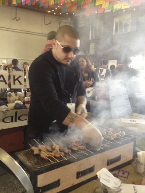 Alchemy chef Ricardo Heredia, sporting sunglasses, turns Japanese skewers over a smoky grill at his Street Food Market stand in the San Diego Public Market on March 24, 2013. (Photo by Cyndia Zwahlen for the Small Biz Mix.)
