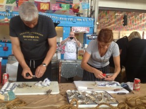 Erik Gosswiller, left, and Maylin Chavez open local oysters at chef Melissa Mayer's Pacific Standard Oyster Co. food cart at the Street Food Market party held March 24, 2013 in the San Diego Public Market. Mayer, who runs Martini Media, is event co-chair.(Photo by Cyndia Zwahlen for the Small Biz Mix.)