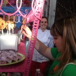 A woman plucks a strawberry-rhubarb pie pop out of its bed of sugar in a glass box on a fanciful pink-metal dessert cart at the Street Food Market party in the San Diego Public Market, March 24, 2013. (Photo by Cyndia Zwahlen for Small Biz Mix)