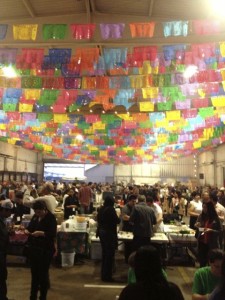Rows of colorful Mexican paper banners (papel picado) wave overhead in the smoky air as hundreds of partygoers sample the goodies at the Street Food Market party held March 24, 2013 at the cavernous San Diego Public Market. (Photo by Cyndia Zwahlen for the Small Biz Mix.)